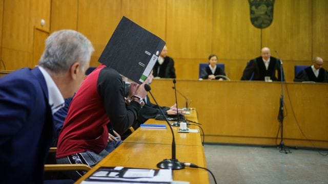 Mit einem Aktenordner vor dem Gesicht nimmt der Iraker Taha Al-J. Mit einem Aktenordner vor dem Gesicht nimmt der Iraker Taha Al-J.