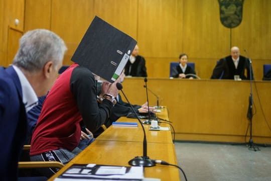Mit einem Aktenordner vor dem Gesicht nimmt der Iraker Taha Al-J.