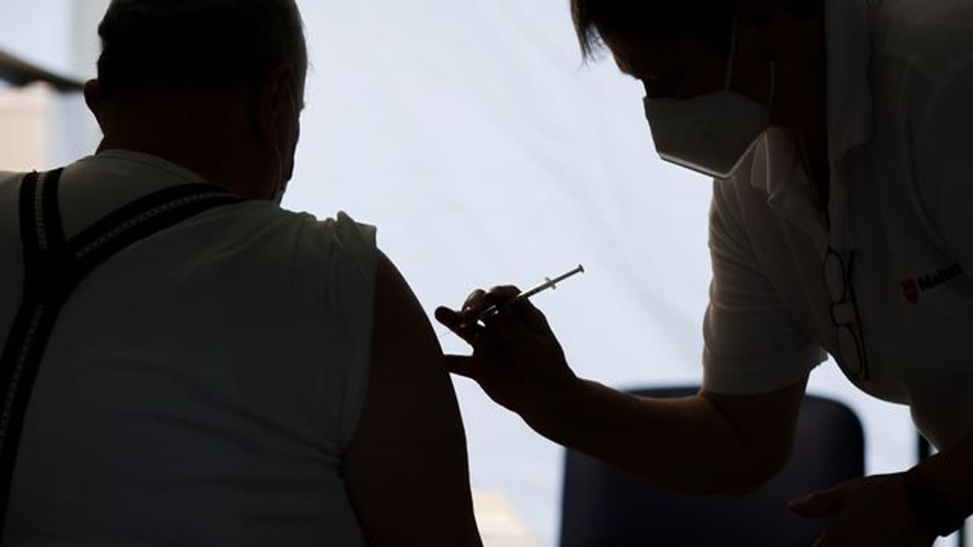 Eine Mitarbeiterin der Malteser impft einen Bürger in einem Impfzentrum in Sachsen-Anhalt.