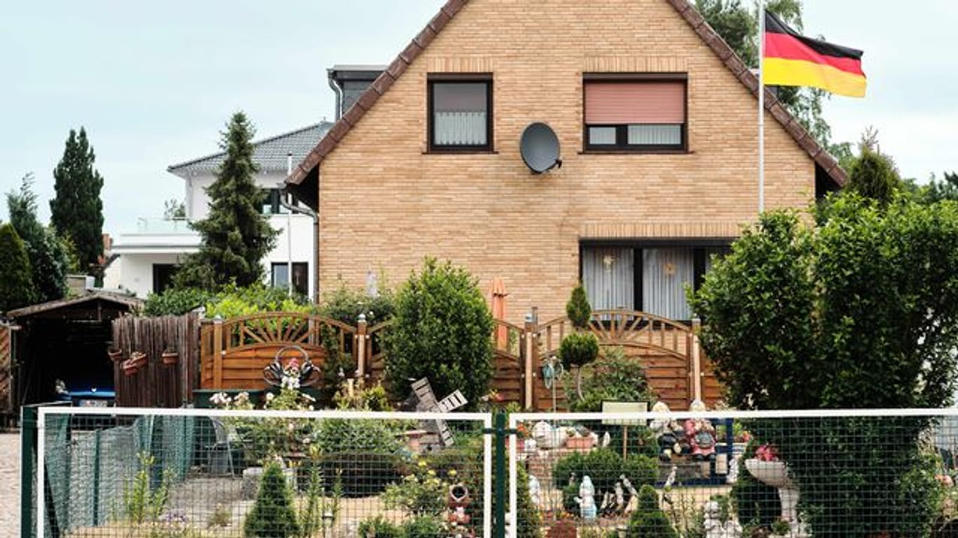Eine Deutschlandfahne weht vor einem Einfamilienhaus.