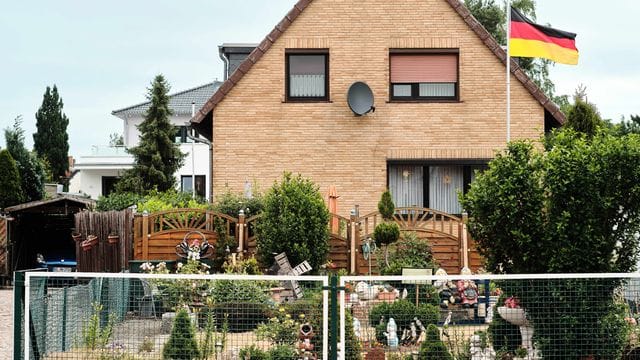 Eine Deutschlandfahne weht vor einem Einfamilienhaus. Eine Deutschlandfahne weht vor einem Einfamilienhaus.