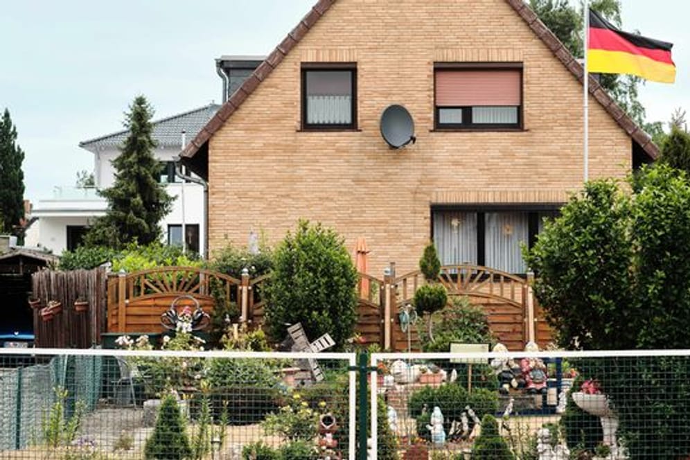 Eine Deutschlandfahne weht vor einem Einfamilienhaus.