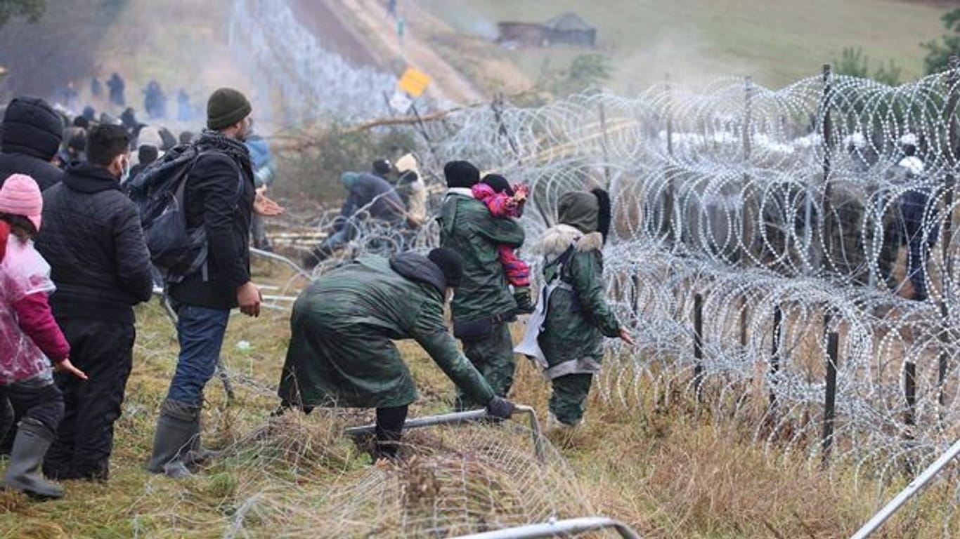 Getrennt durch Stacheldraht: Migranten stehen an der Grenze auf der belarussischen Seite - auf der polnischen stehen Sicherheitskräfte.