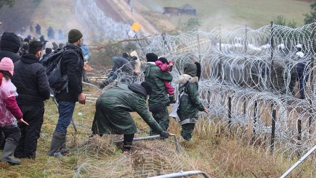 Getrennt durch Stacheldraht: Migranten stehen an der Grenze auf der belarussischen Seite - auf der polnischen stehen Sicherheitskräfte. Getrennt durch Stacheldraht: Migranten stehen an der Grenze auf der belarussischen Seite - auf der polnischen stehen Sicherheitskräfte.