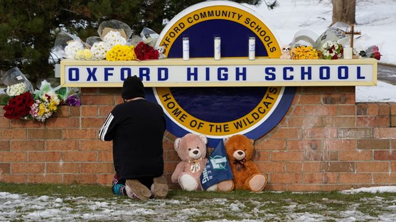 Eine Frau kniet zum Gebet vor dem Schild der Oxford High School im US-Bundesstaat Michigan.