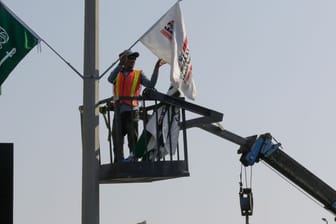 Ein Mitarbeiter hängt Flaggen an der Rennstrecke des Corniche Circuit auf: Die Formel 1 gastiert erstmals in Saudi-Arabien.