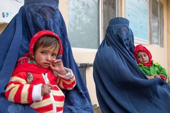 Zwei afghanische Frauen warten mit ihren Kindern vor einer Klinik für Ernährungsfragen.
