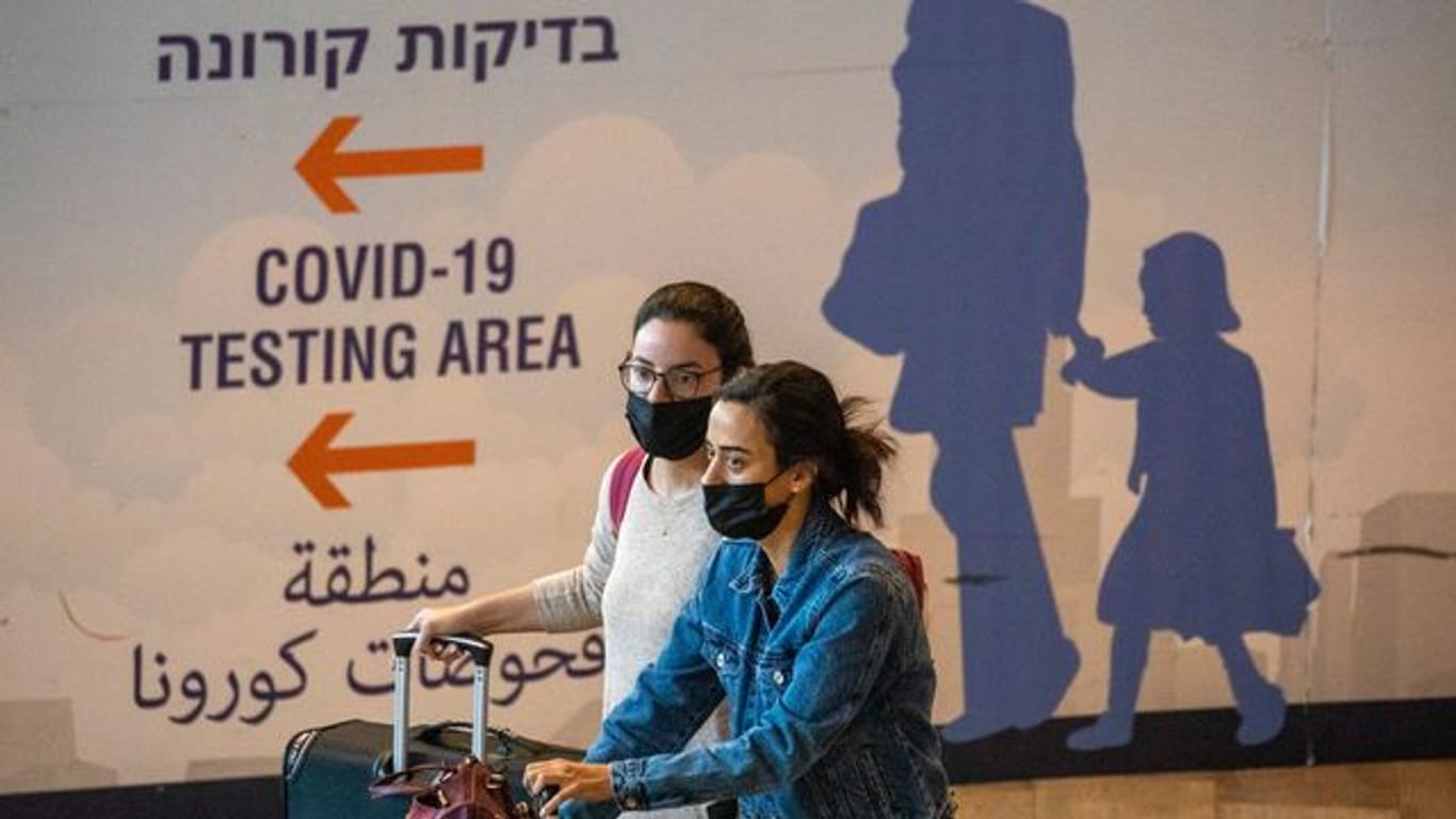 Reisende mit Mund-Nasen-Schutz kommen am Ben-Gurion-Flughafen an.