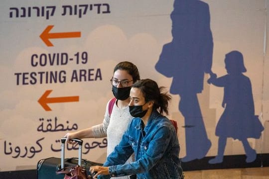 Reisende mit Mund-Nasen-Schutz kommen am Ben-Gurion-Flughafen an.