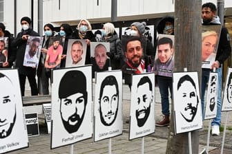 Angehörige der Opfer des rassistischen Anschlags von Hanau 2020 halten bei einer Mahnwache vor dem hessischen Landtag Fotos der Opfer.
