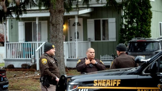 Deputies des Oakland County Sheriffs untersuchen das Gelände vor dem Haus der Eltern des mutmaßlichen Täters. Deputies des Oakland County Sheriffs untersuchen das Gelände vor dem Haus der Eltern des mutmaßlichen Täters.