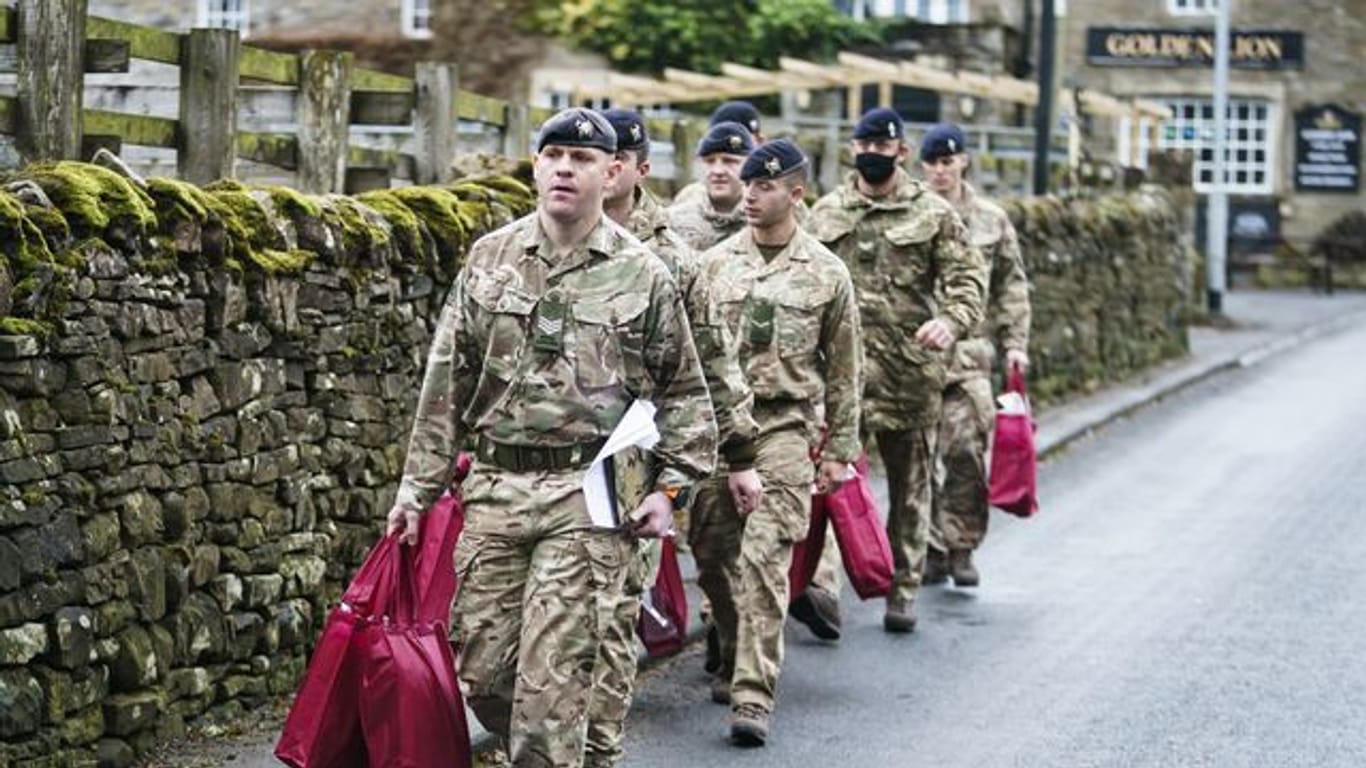 Angehörige der Streitkräfte tragen Versorgungspakete, um sie an Betroffene im britischen St.