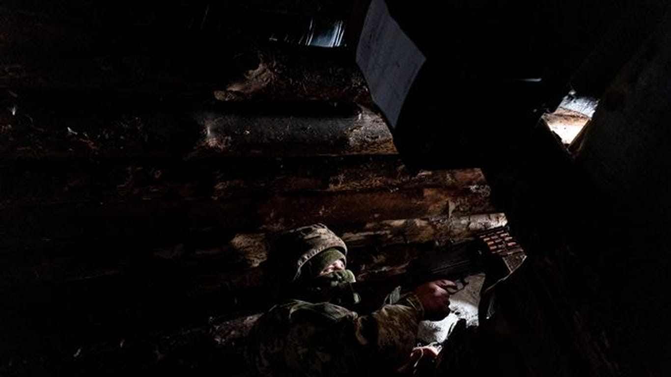 Ein ukrainischer Soldat hält sich schussbereit mit einem Maschinengewehr in einem Unterschlupf auf.