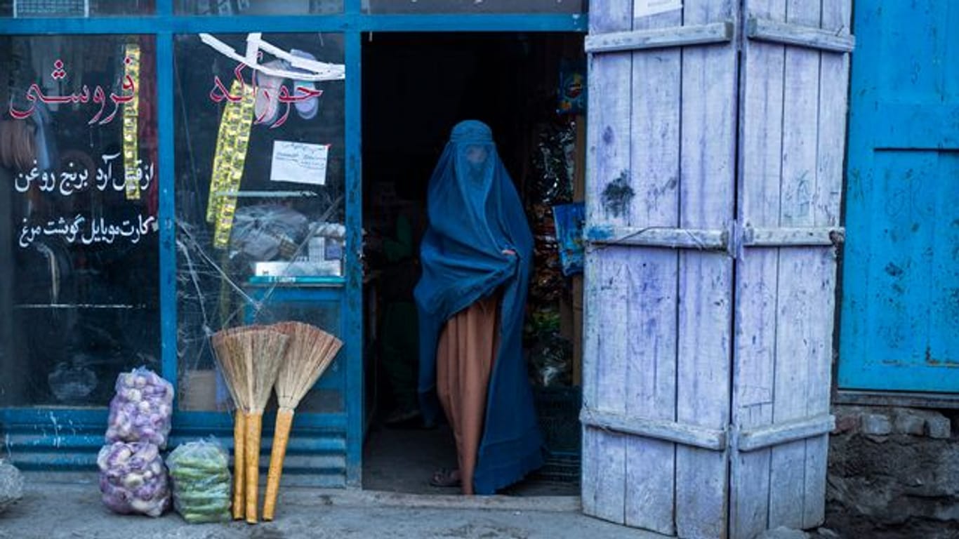 Eine afghanische Frau, die eine Burka trägt, verlässt einen kleinen Laden in Kabul (Archivbild).