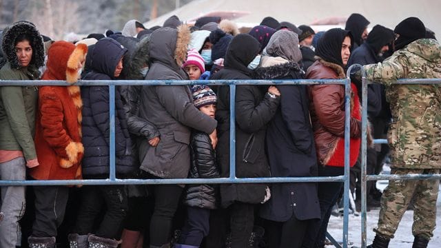 Das von der belarussischen Staatsagentur BelTA zur Verfügung gestellte Foto zeigt Migranten, die in einem Logistikzentrum an der belarussisch-polnischen Grenze für Essen anstehen.