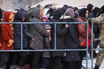 Das von der belarussischen Staatsagentur BelTA zur Verfügung gestellte Foto zeigt Migranten, die in einem Logistikzentrum an der belarussisch-polnischen Grenze für Essen anstehen.