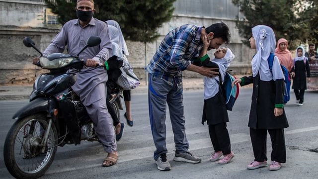 Ein junges afghanisches Mädchen gibt ihrem Vater einen Kuss, bevor sie eine Grundschule in Kabul besucht.