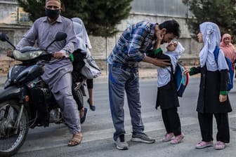 Ein junges afghanisches Mädchen gibt ihrem Vater einen Kuss, bevor sie eine Grundschule in Kabul besucht.