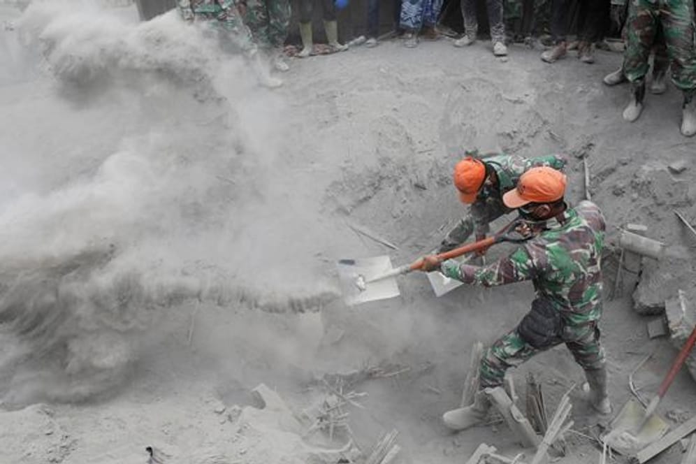 Soldaten suchen nach Opfern, nachdem ein Haus unter der Vulkanasche verschüttet wurde.