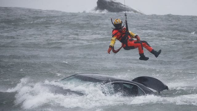 Ein Taucher der US-Küstenwache wird aus einem Hubschrauber abgelassen, um ein Opfer aus einem Fahrzeug zu bergen. Ein Taucher der US-Küstenwache wird aus einem Hubschrauber abgelassen, um ein Opfer aus einem Fahrzeug zu bergen.