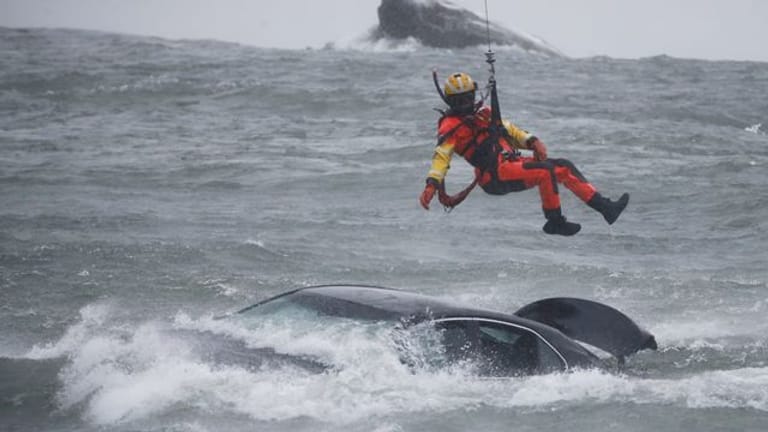 Ein Taucher der US-Küstenwache wird aus einem Hubschrauber abgelassen, um ein Opfer aus einem Fahrzeug zu bergen.