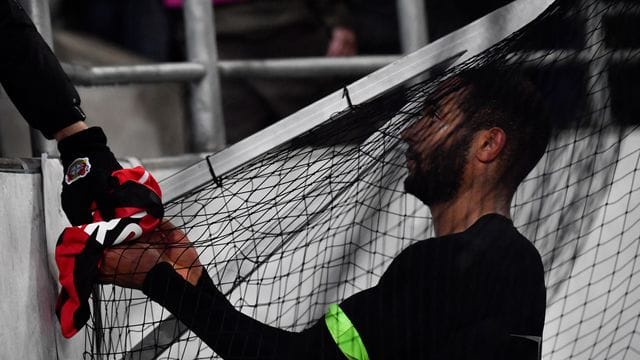 Leverkusens Jonathan Tah präsentiert einem Fan sein Trikot nach der Partie.