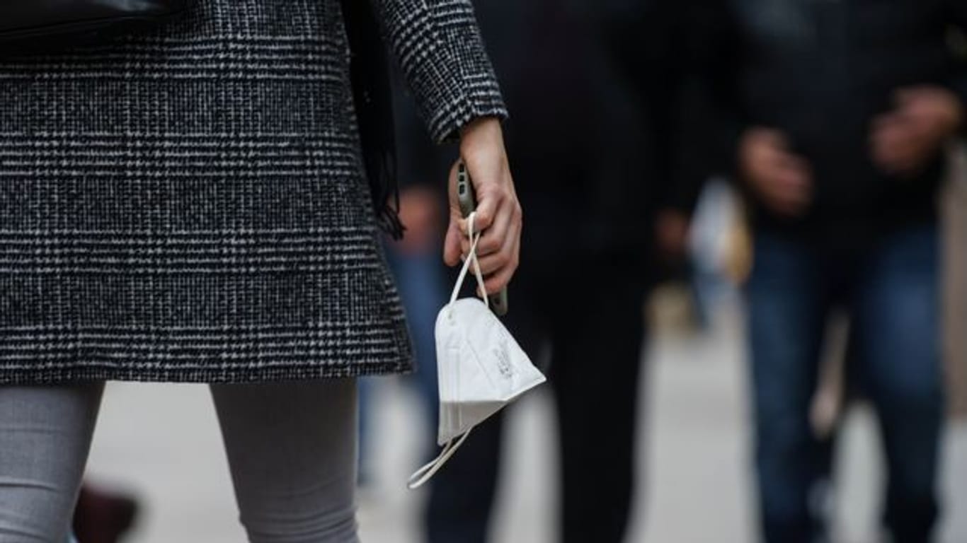 Eine Frau trägt am Nachmittag auf der Frankfurter Einkaufsmeile Zeil eine FFP-2-Maske in der Hand.