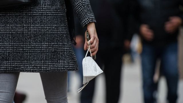 Eine Frau trägt am Nachmittag auf der Frankfurter Einkaufsmeile Zeil eine FFP-2-Maske in der Hand. Eine Frau trägt am Nachmittag auf der Frankfurter Einkaufsmeile Zeil eine FFP-2-Maske in der Hand.