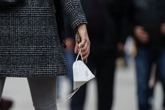 Eine Frau trägt am Nachmittag auf der Frankfurter Einkaufsmeile Zeil eine FFP-2-Maske in der Hand.