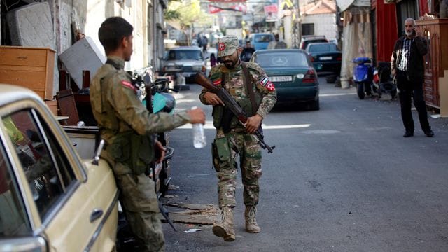 Palästinensische Kämpfer halten am Tag nach den Explosionen im Flüchtlingslager Burdsch al-Schimali Wache.