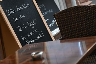 Auf einer Tafel vor einem Restaurant am Frankfurter Römerberg steht der Hinweis "Bitte beachten Sie die "2-G-Regel" in unserem Restaurant!".