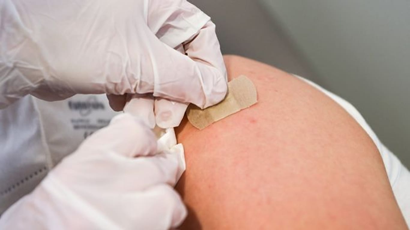 Eine Ärztin klebt nach einer Impfung ein Pflaster auf die Einstichstelle.