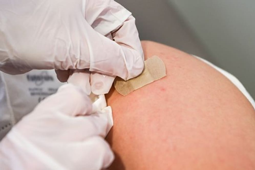 Eine Ärztin klebt nach einer Impfung ein Pflaster auf die Einstichstelle.