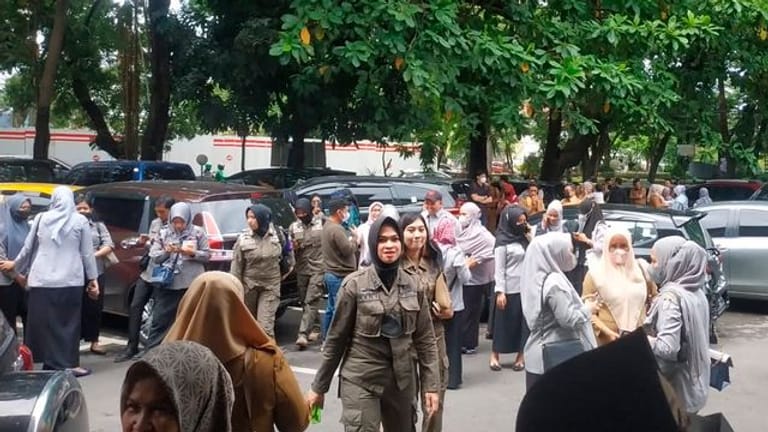 Menschen warten draußen, nachdem sie ein Regierungsgebäude nach einem Erdbeben in Makassar, Südsulawesi, Indonesien, evakuiert haben.