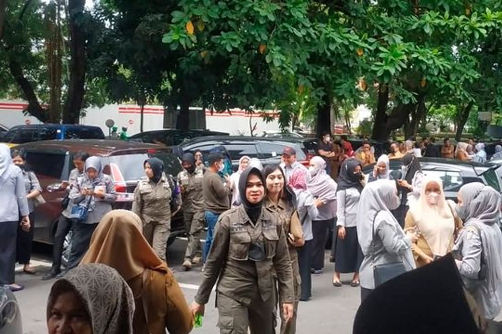 Menschen warten draußen, nachdem sie ein Regierungsgebäude nach einem Erdbeben in Makassar, Südsulawesi, Indonesien, evakuiert haben.