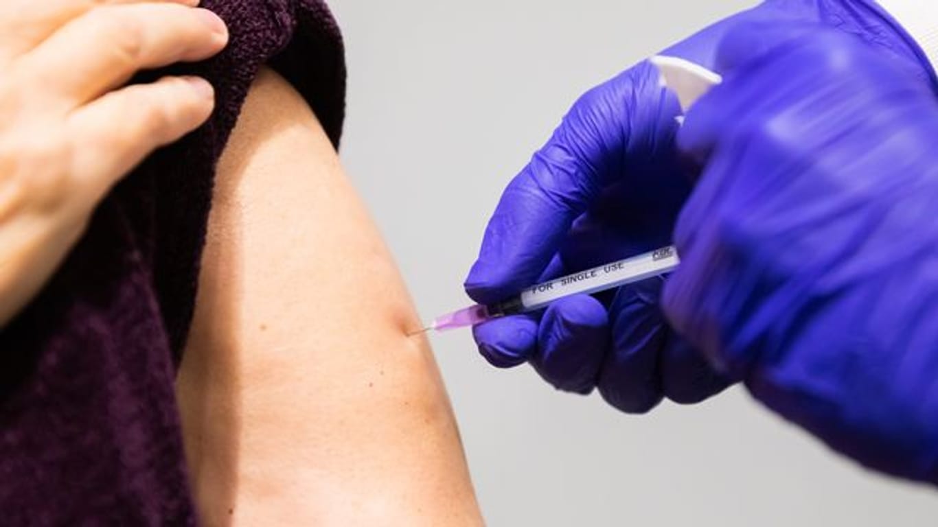 Ein Arzt führt in einer Impfstelle eine Booster-Impfung durch.