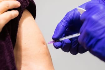 Ein Arzt führt in einer Impfstelle eine Booster-Impfung durch.