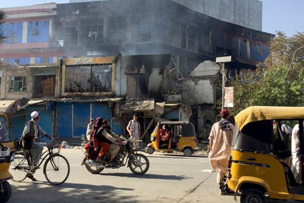 Menschen fahren in Kundus an Trümmern von Geschäften vorbei, die bei Zusammenstößen zwischen den Taliban und afghanischen Sicherheitskräften zerstört wurden.