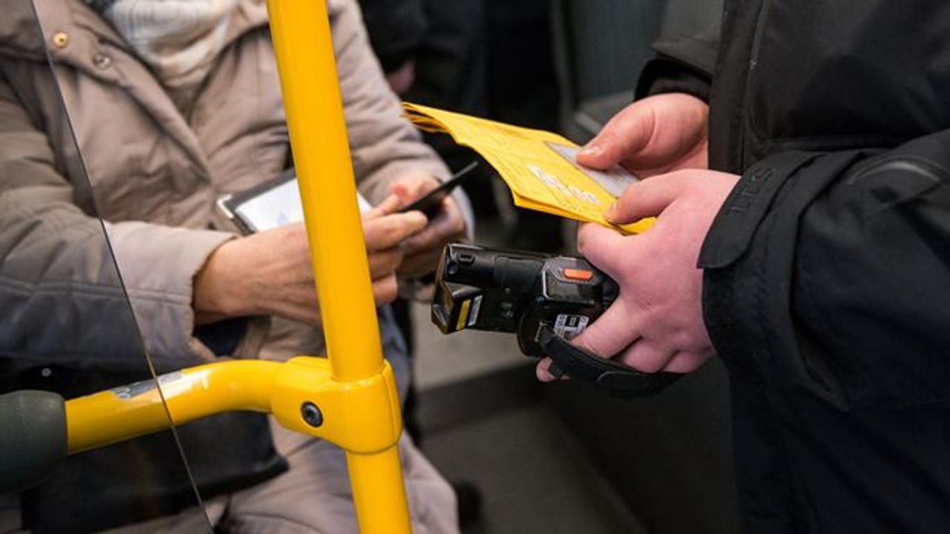 Ein Prüfdienst-Mitarbeiter der Verkehrsbetriebe Hamburg-Holstein (VHH) kontrolliert in einem Bus den 3-G-Nachweis einer Passagierin.