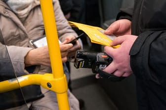 Ein Prüfdienst-Mitarbeiter der Verkehrsbetriebe Hamburg-Holstein (VHH) kontrolliert in einem Bus den 3-G-Nachweis einer Passagierin.
