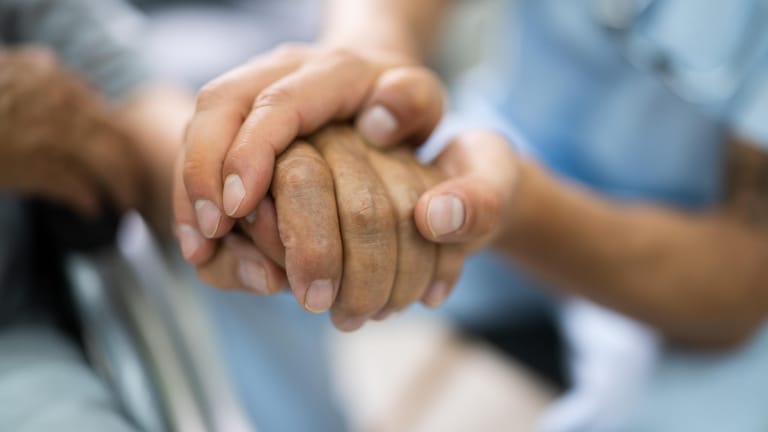 Ein Pfleger hält die Hand eines Patienten (Symbolbild): Frankreichs ältester Mann erkrankte schwer an Corona.