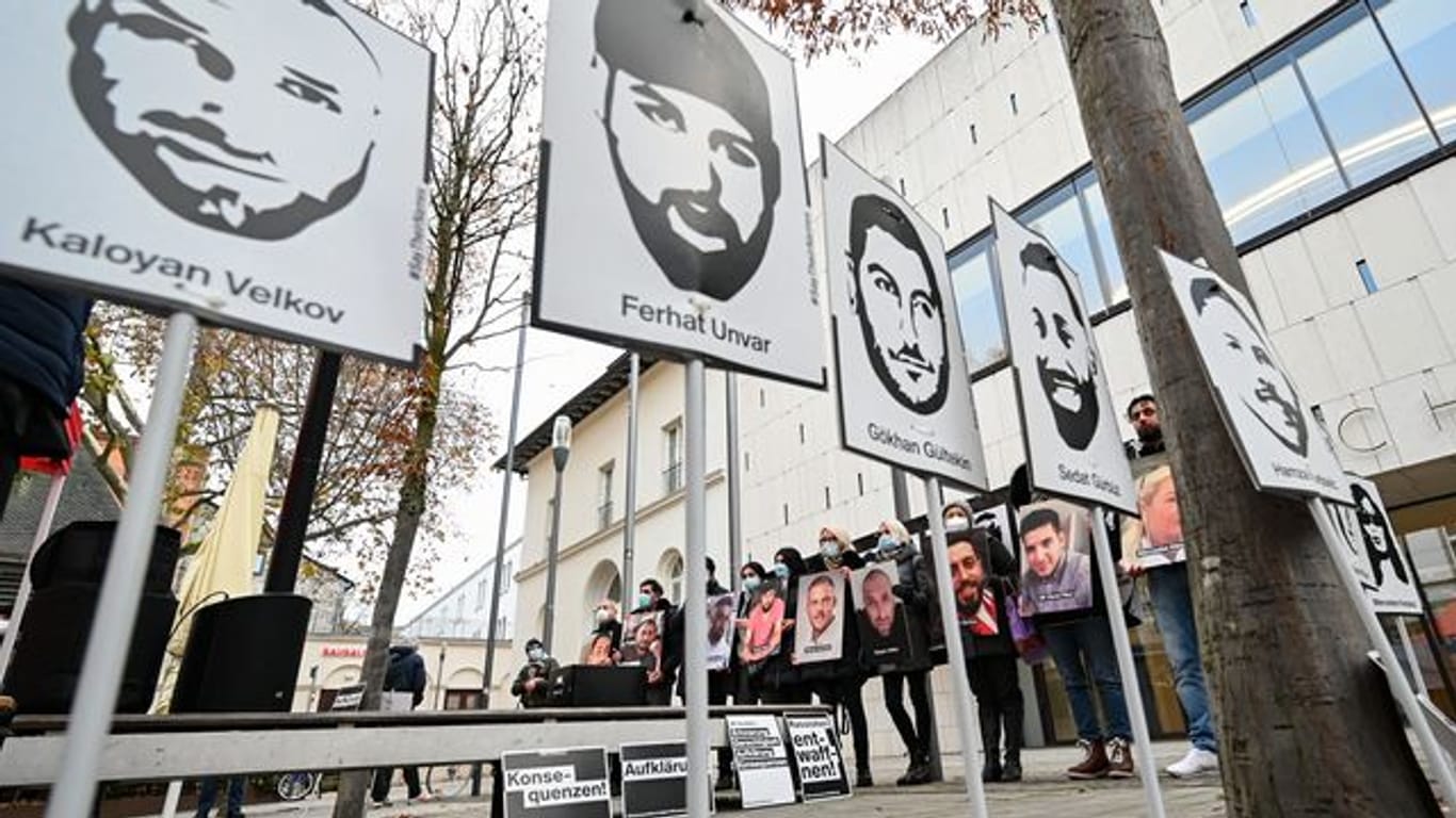 Angehörige der Opfer des rassistischen Anschlags von Hanau 2020 halten bei einer Mahnwache Fotos der Opfer.