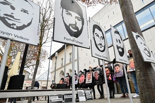 Angehörige der Opfer des rassistischen Anschlags von Hanau 2020 halten bei einer Mahnwache Fotos der Opfer.