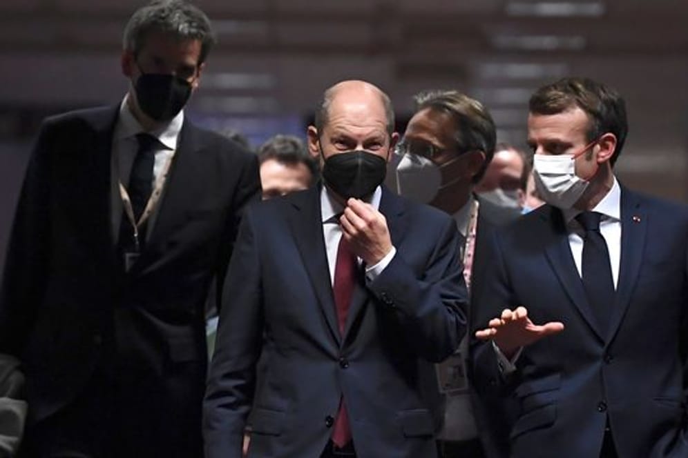 Bundeskanzler Olaf Scholz (M) und Frankreichs Präsident Emmanuel Macron (r) vor der abschließenden Pressekonferenz des EU-Gipfels.