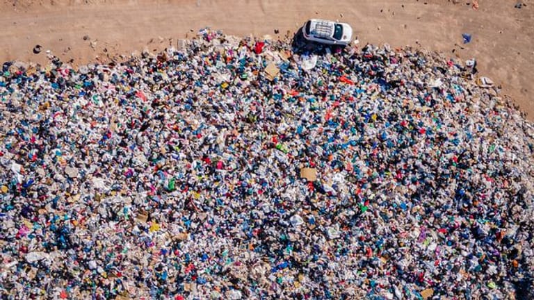 Gebrauchte Kleidungsstücke liegen der Müll-Deponie in der Wüste.