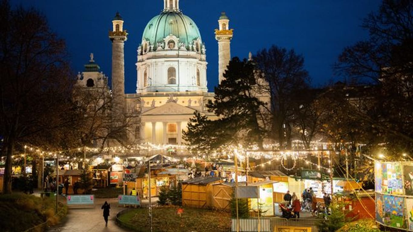 Menschen besuchen den Christkindlmarkt am Karlsplatz in Wien.