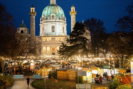 Menschen besuchen den Christkindlmarkt am Karlsplatz in Wien.
