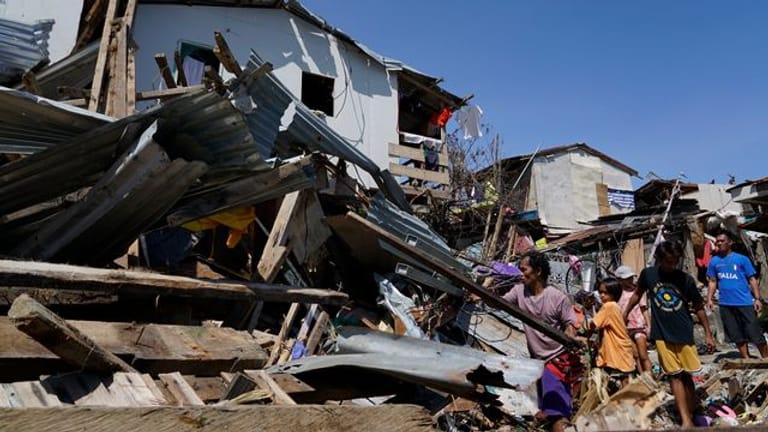 Bewohner suchen in den zerstörten Häusern nach Habseligkeiten.