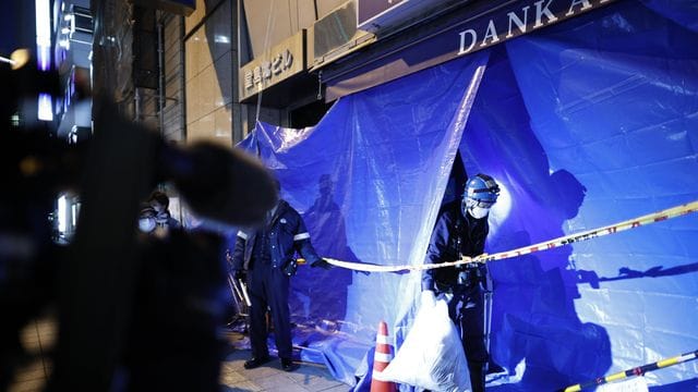 Polizisten ermitteln in dem abgesperrten Mehrfamilienhaus in Osaka, in dem es zu dem tödlichen Brand gekommen ist. Polizisten ermitteln in dem abgesperrten Mehrfamilienhaus in Osaka, in dem es zu dem tödlichen Brand gekommen ist.