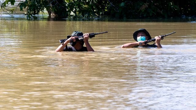 Zwei Soldaten waten durch eine überflutete Straße.